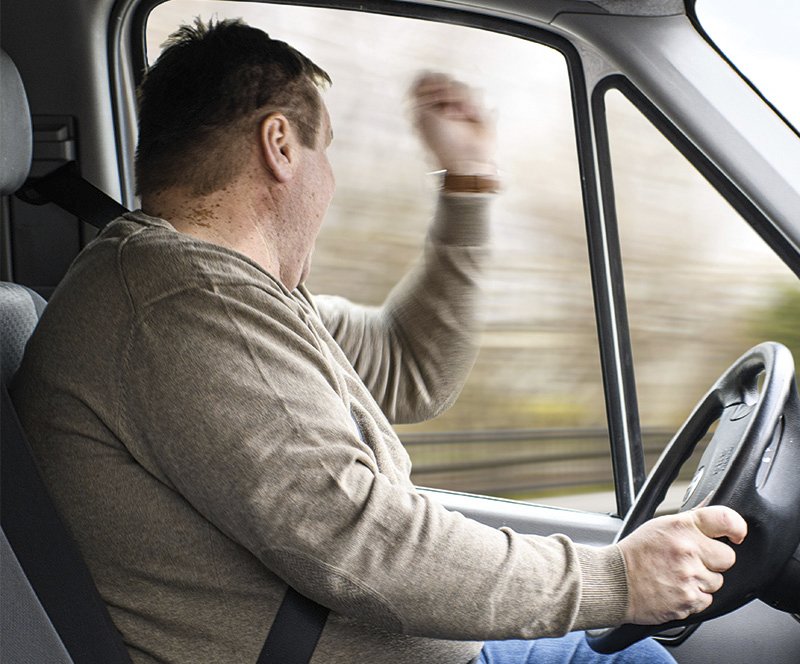 ein Autofahrer die mit erhobenem Arm aus dem Fenster schreit