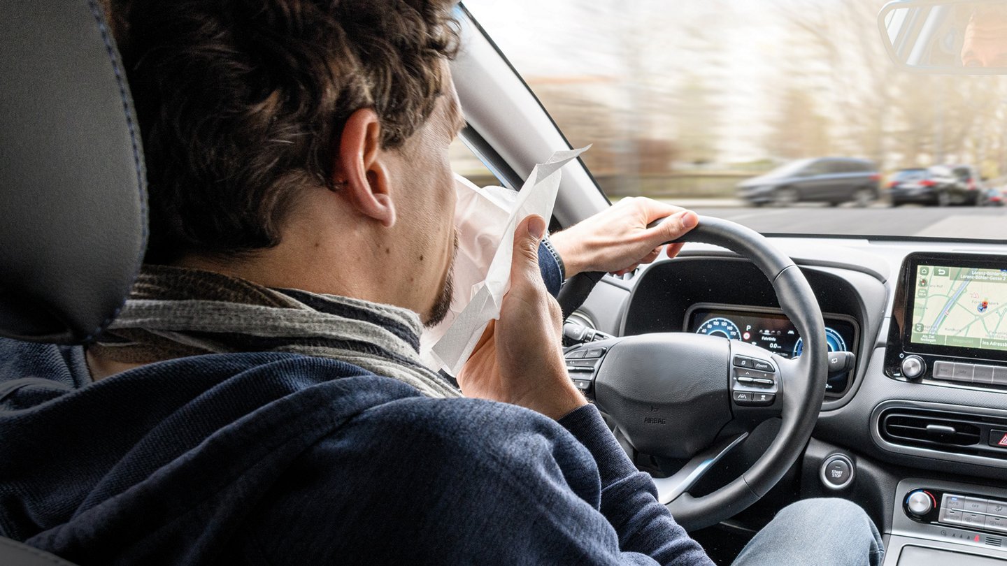 ein Autofahrer hält sich ein Taschentuch vor die Nase