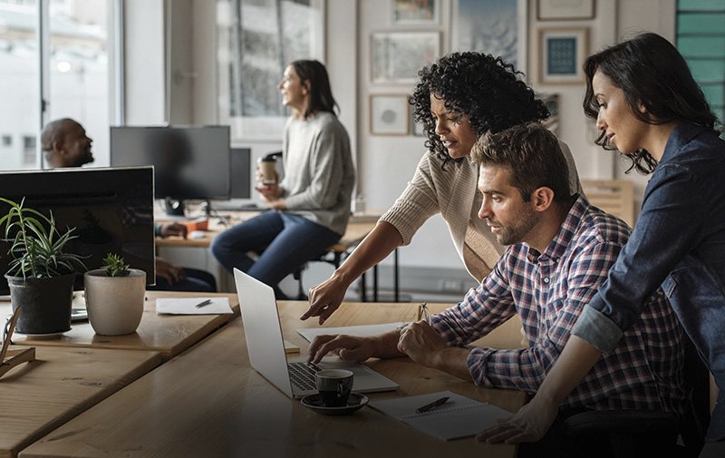 Team arbeitet gemeinsam konzentriert an einem Laptop im Büro.