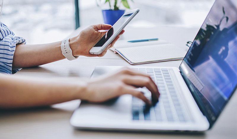 Eine Person arbeitet an Laptop und Smartphone – 