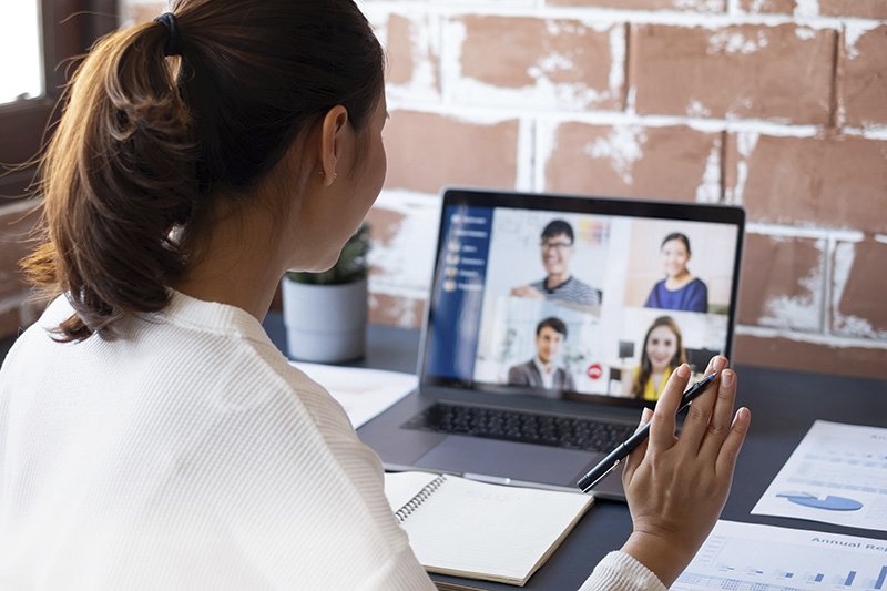 Person nimmt an einer Videokonferenz teil und macht sich Notizen.