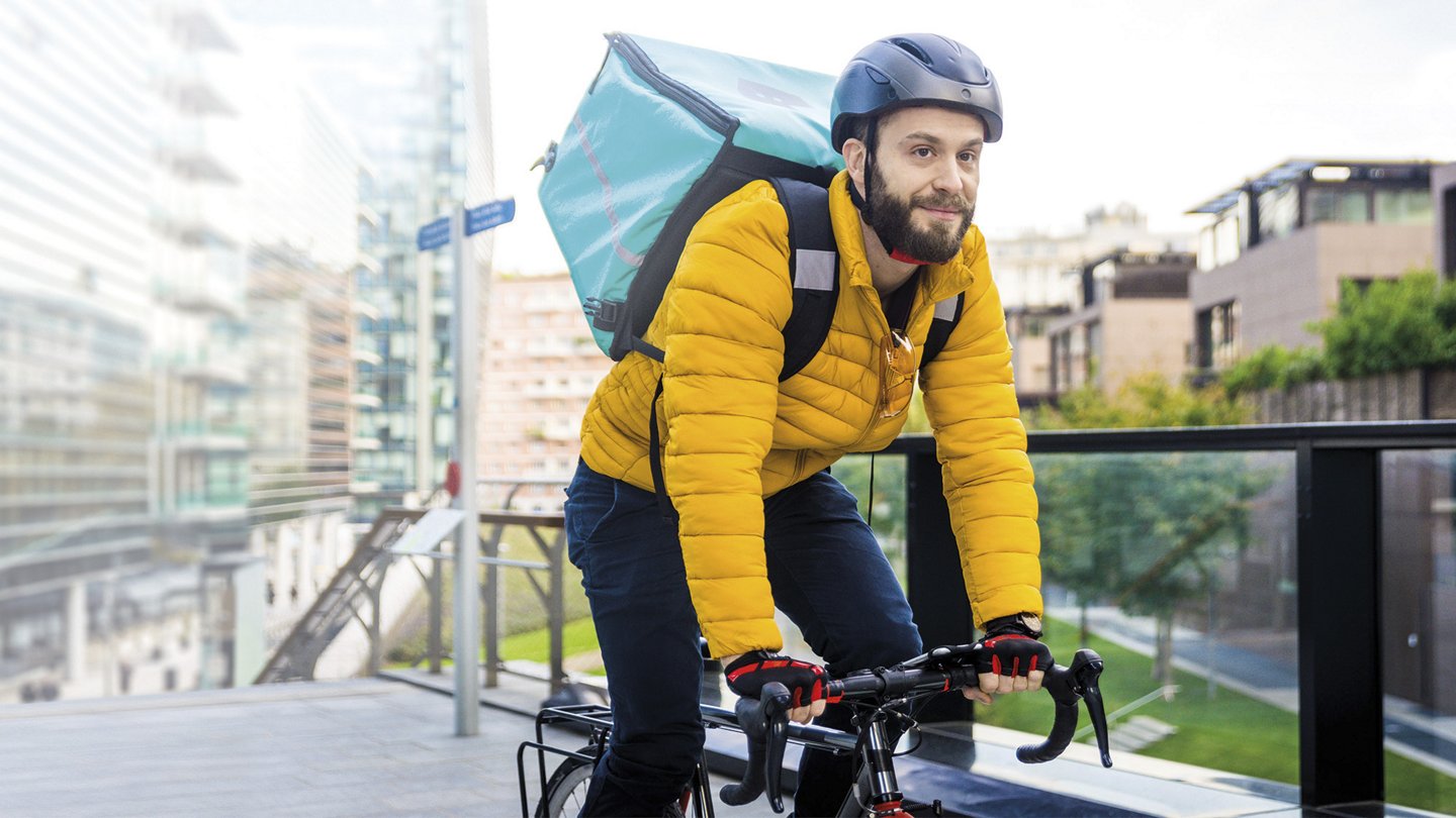 ein männlicher Fahrradkurier mit dicker Jacke und Helm