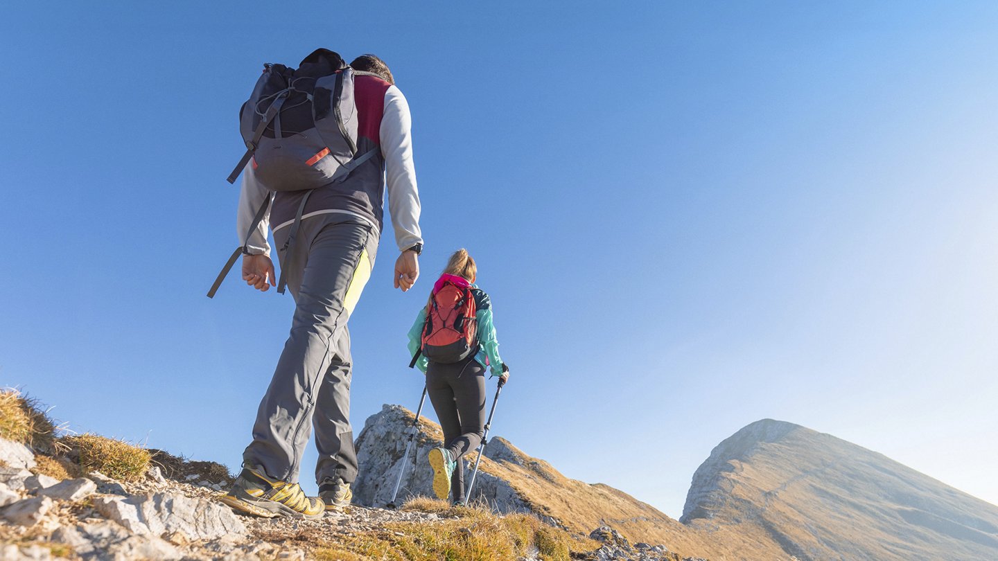 ein Mann und eine Frau mit Rucksack wandern in den Bergen