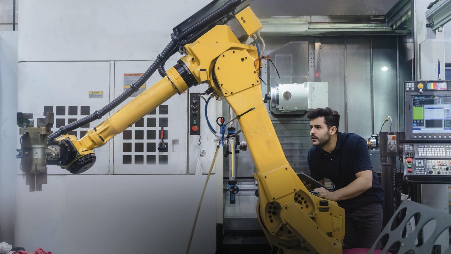 ein Mann steuert einen Roboterarm, der ein Stück Stoff anhebt