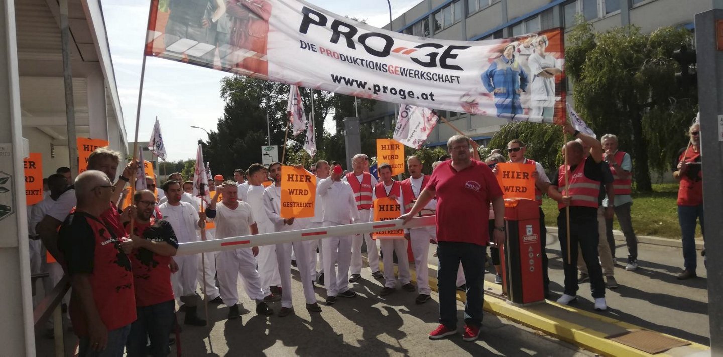 Streikende vor der Werkseinfahrt zur Firma Ardo mit einem PRO-GE Transparent und Plakaten mit der Aufschrift "Hier wird gestreikt!".