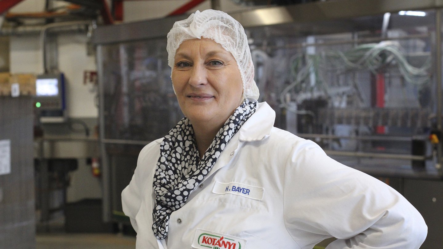 Betriebsrätin Helga Bayer in der Produktionshalle mit Arbeitsgewand.