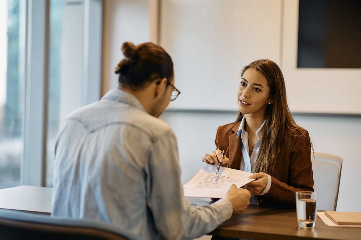 Young bank manager going through agreement with her client during meeting in office., Young bank manager going through agreement with her client durin