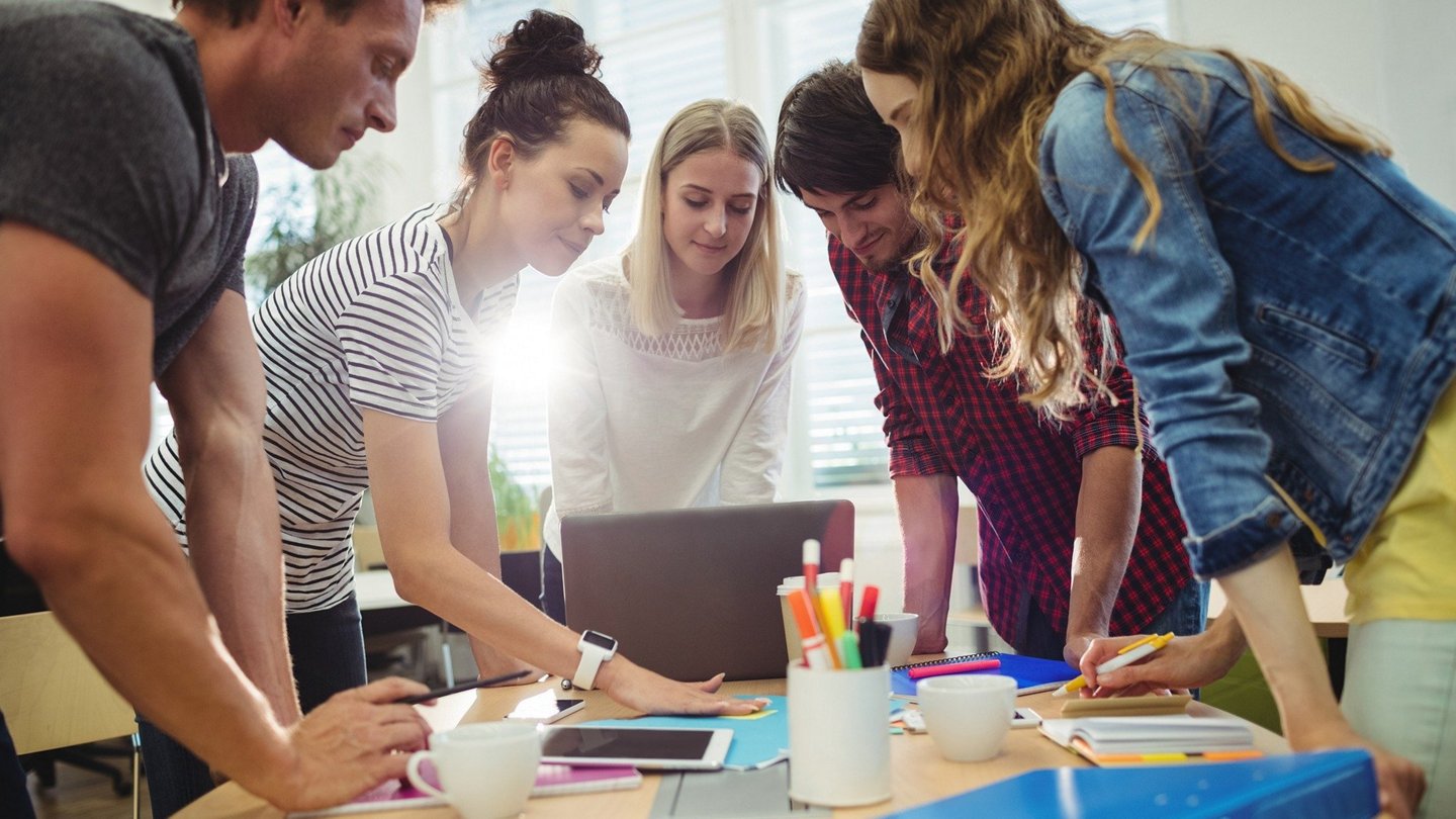 Junge Menschen um einen Tisch bei der Eventplanung 