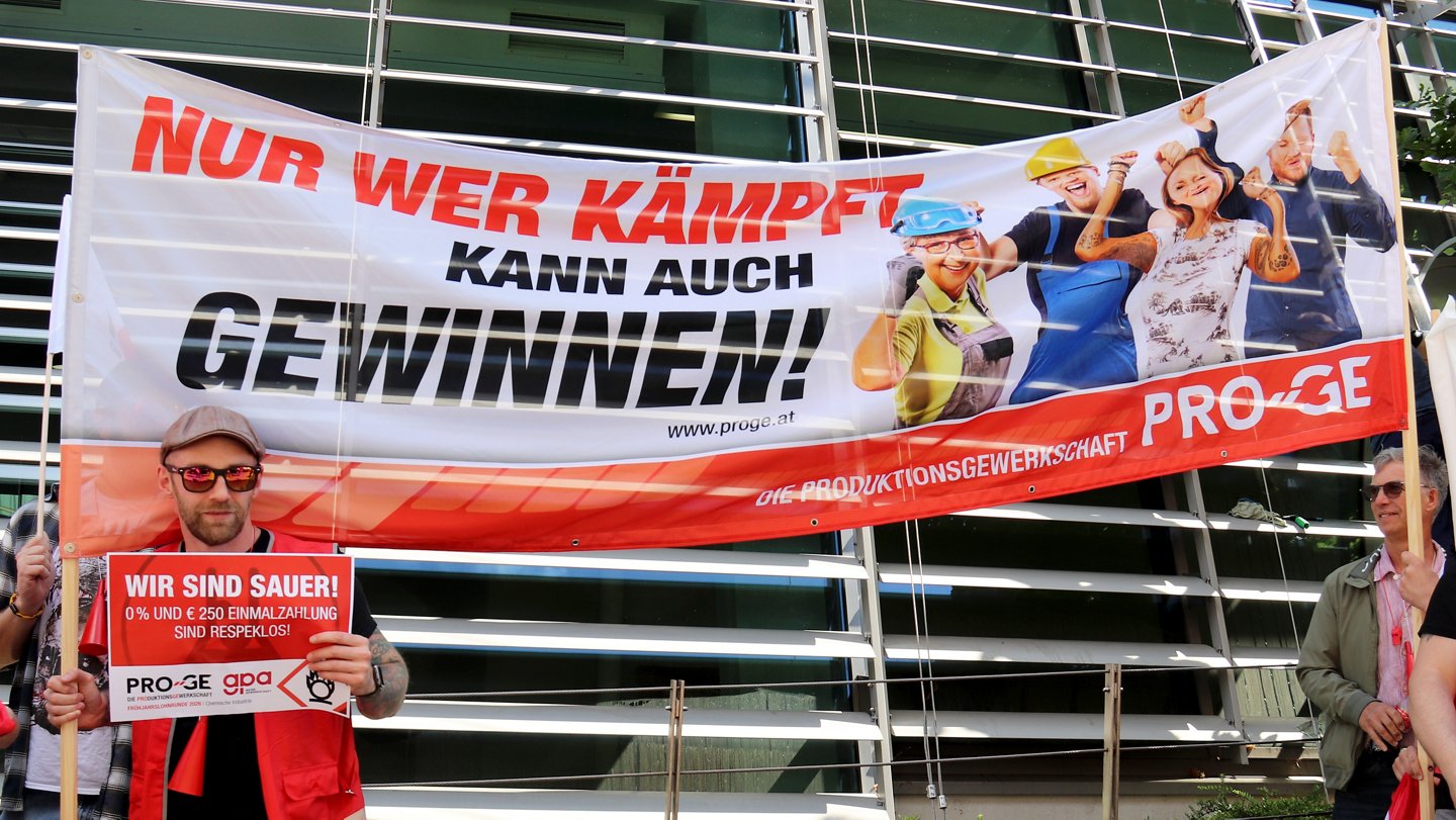 Kundgebungs-Teilnehmer hält großes Transparent "Nur wer kämpft kann auch gewinnen!" und Schild "Wir sind sauer!"