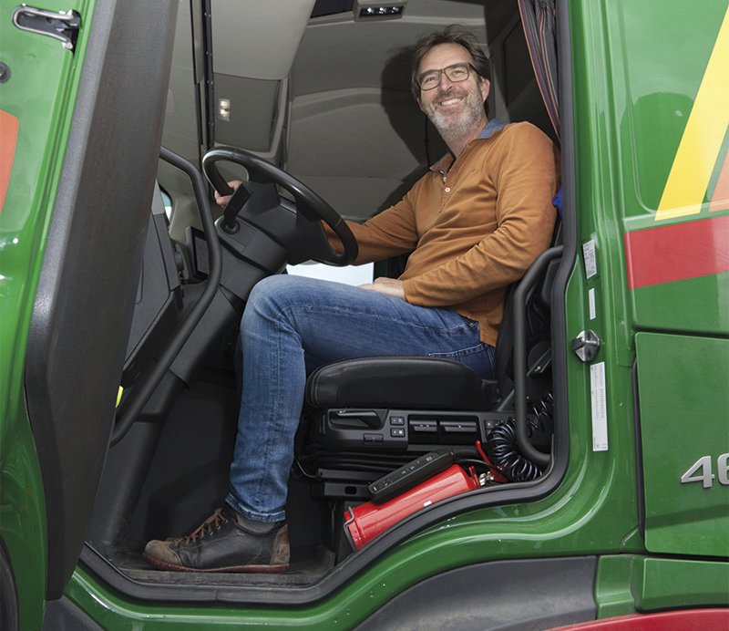 ein Mann sitzt in einem LKW und lächelt bei geöffneter Türe heraus