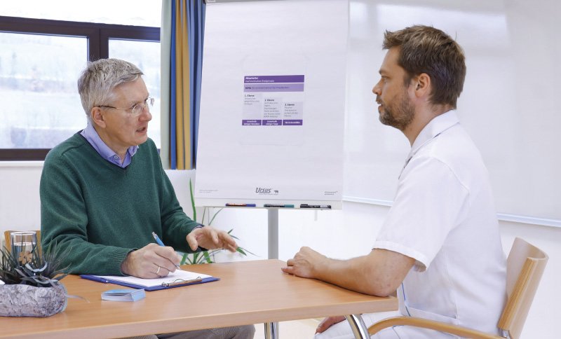Zwei Männer sitzen einander gegenüber und führen ein Gespräch in einem Besprechungsraum.