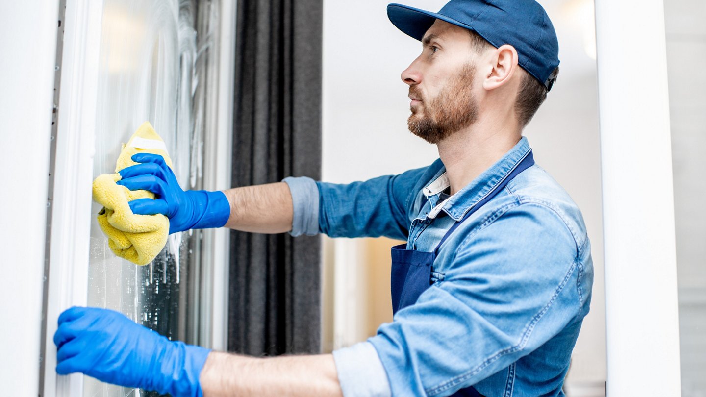 Mann putzt Fenster