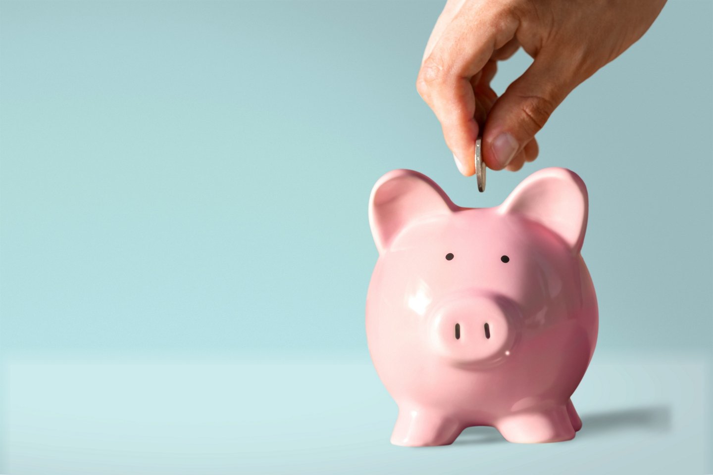 Hand putting coin to piggy bank