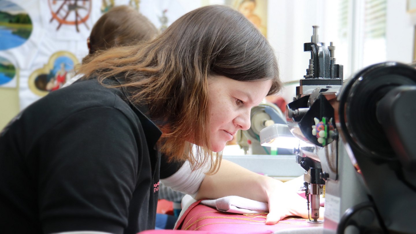 Eine Frau arbeitet genau an einer Stickmaschine