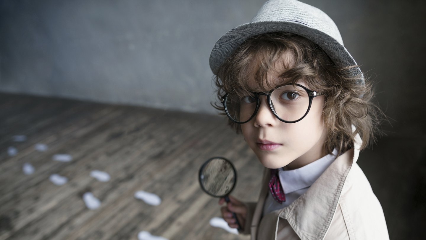 Kind mit Sherlock Holmes Kleidung und Lupe und Fußspuren am Boden