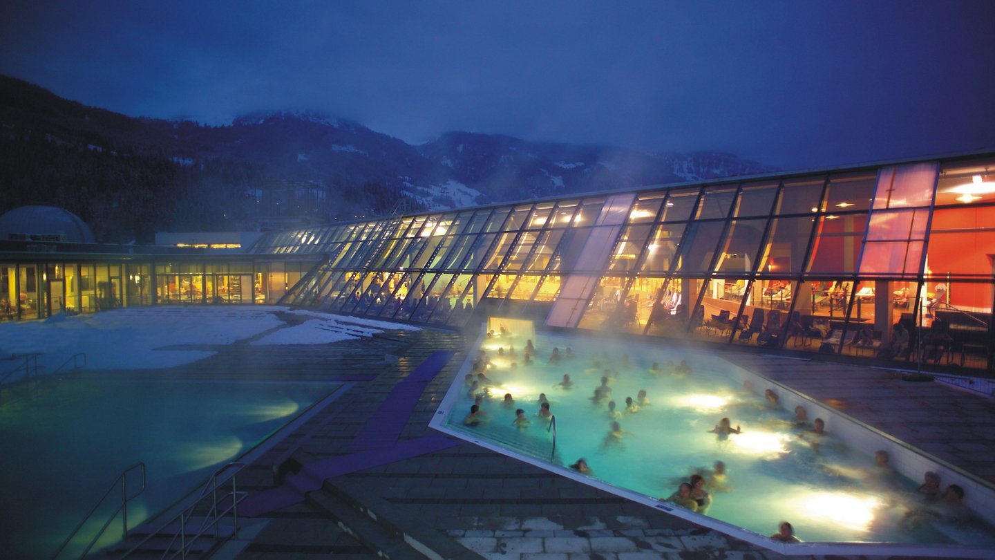 Alpentherme Gastein von außen im Winter mit badenden Menschen